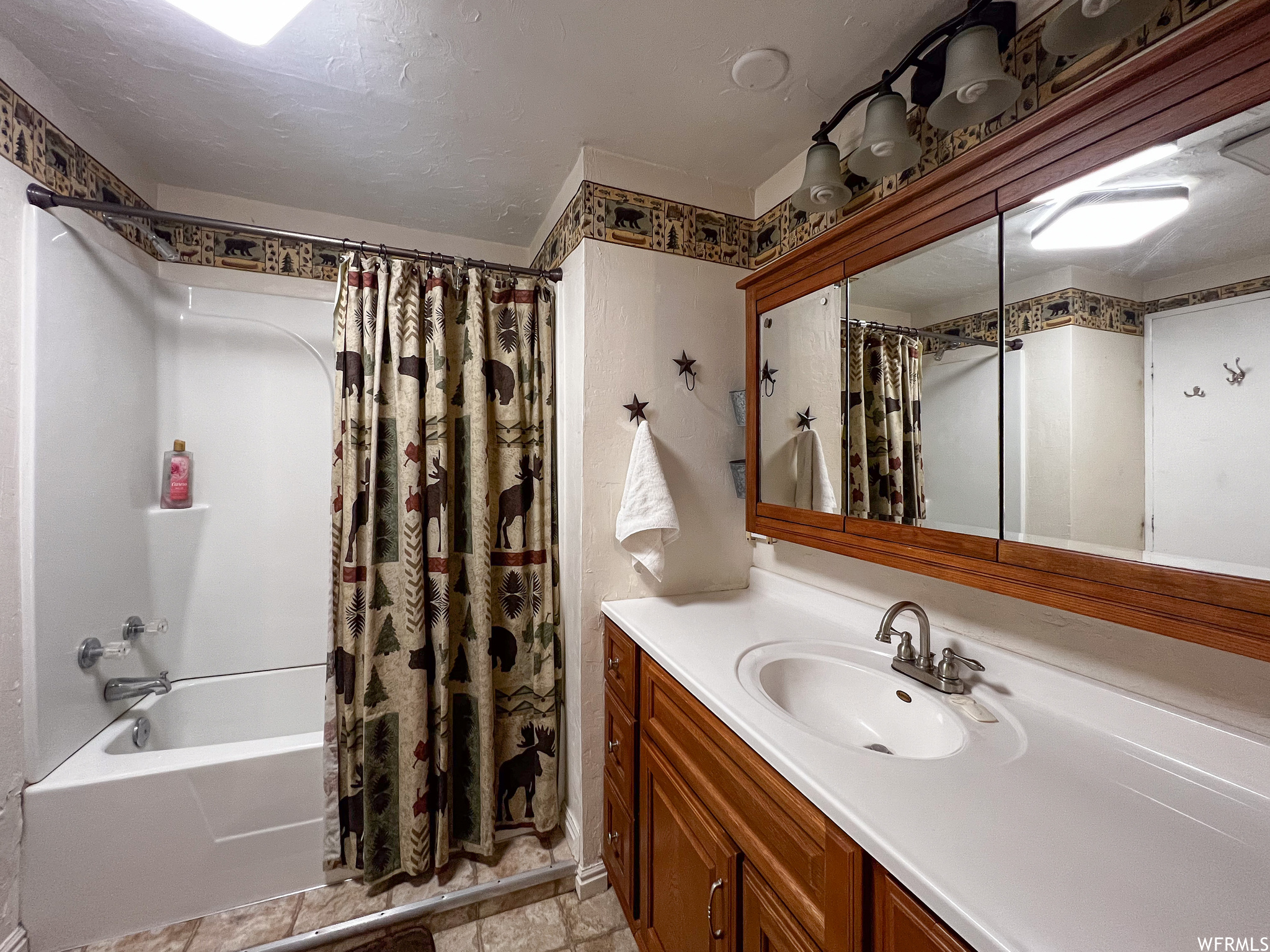 Bathroom with shower / tub combo, tile floors, and vanity with extensive cabinet space