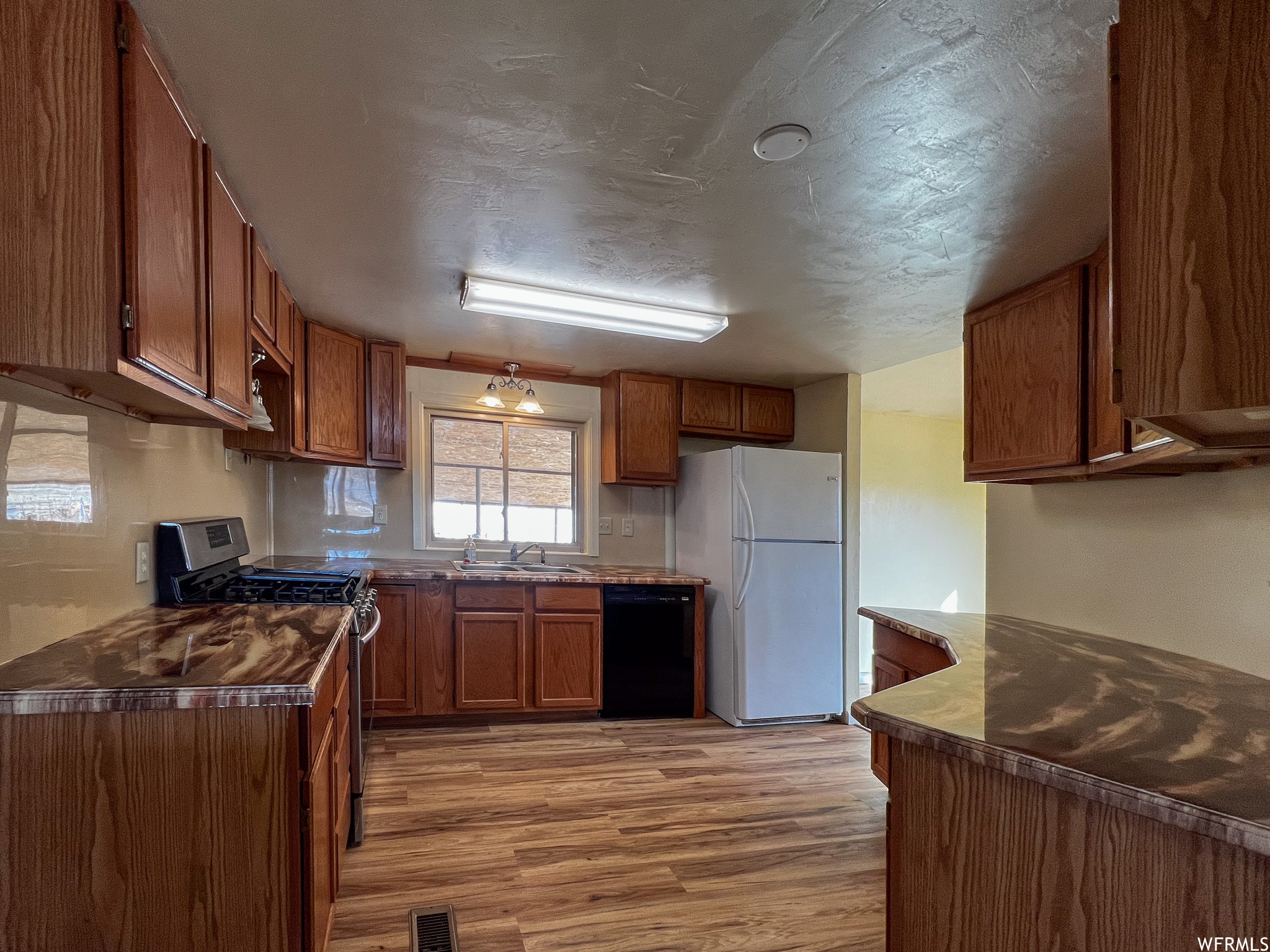 Kitchen featuring white fridge, dishwasher, sink, stainless steel range oven, and light hardwood / wood-style flooring