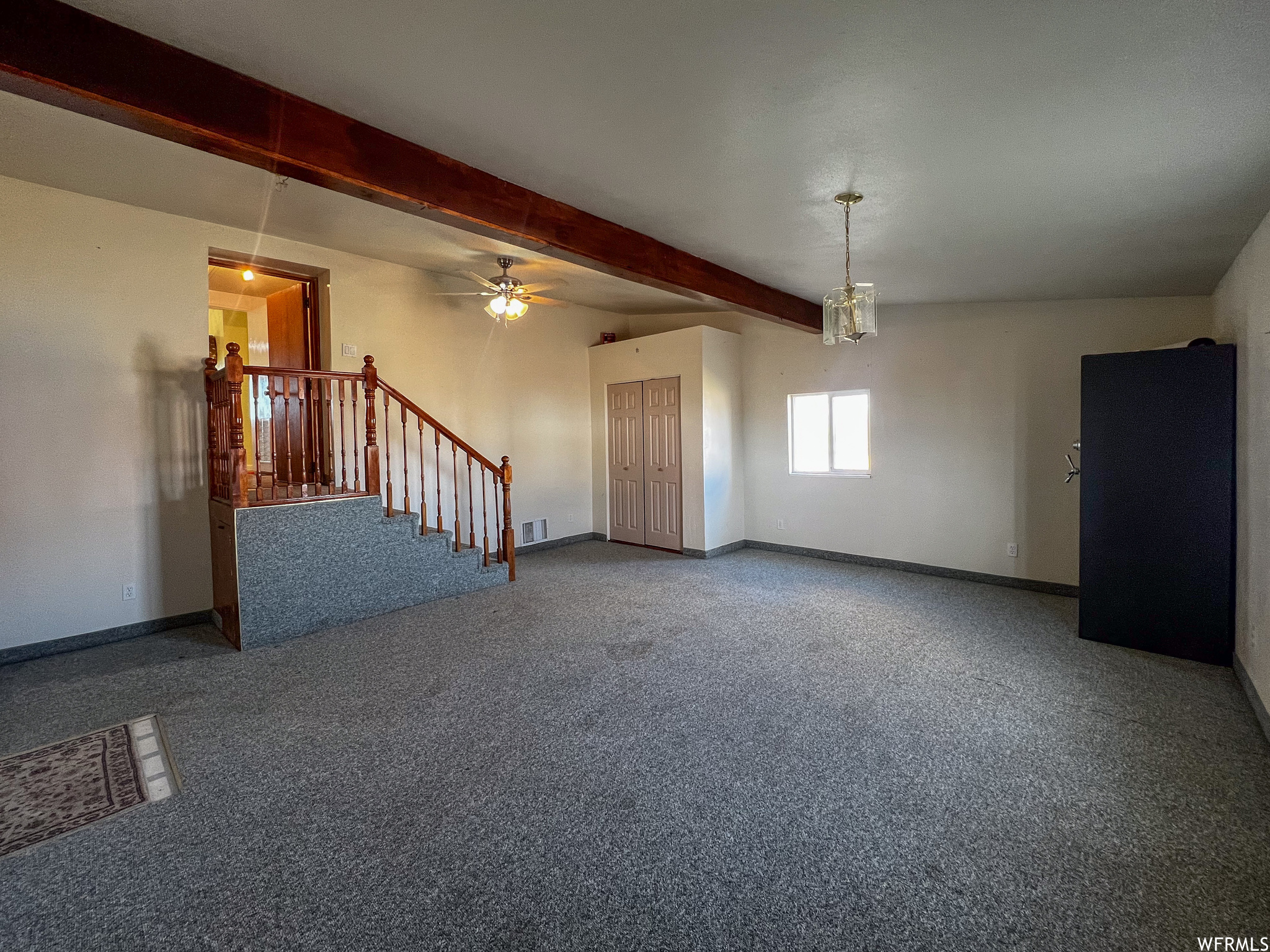 Carpeted spare room with ceiling fan and beam ceiling