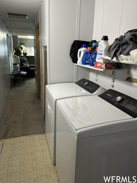 Washroom featuring washing machine and dryer and light carpet