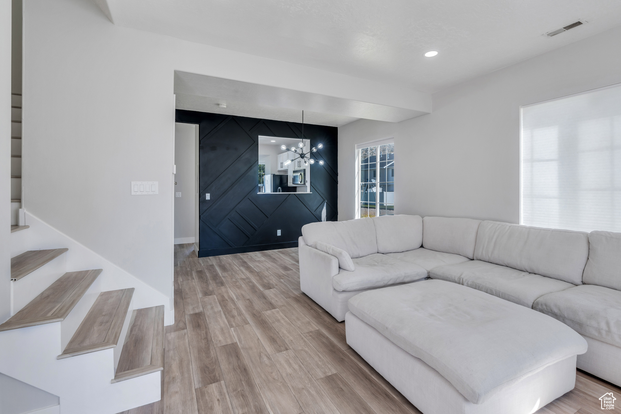 Living room with light hardwood / wood-style flooring, a chandelier, and a wealth of natural light