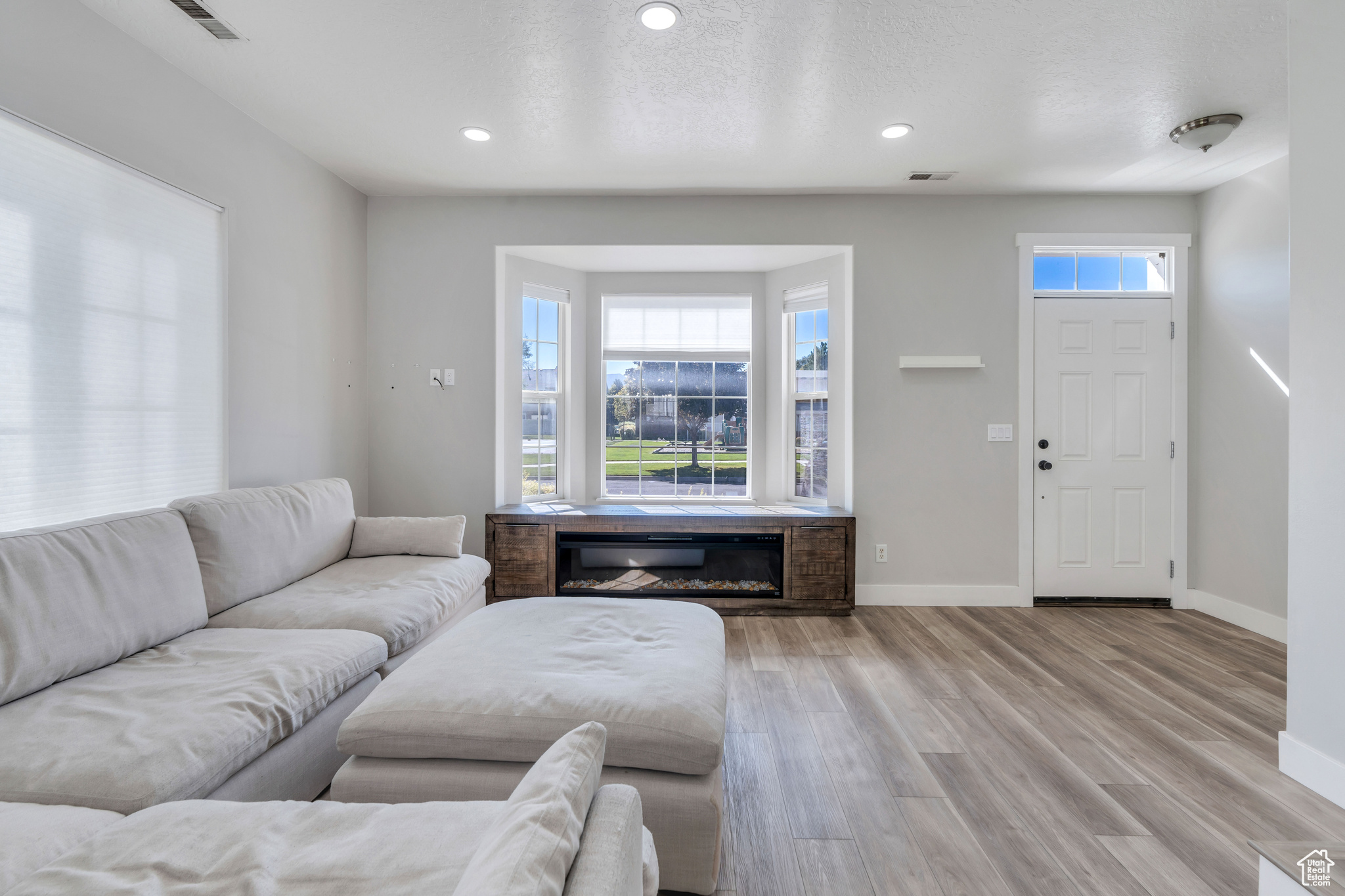 Living room with a textured ceiling and light hardwood / wood-style floors