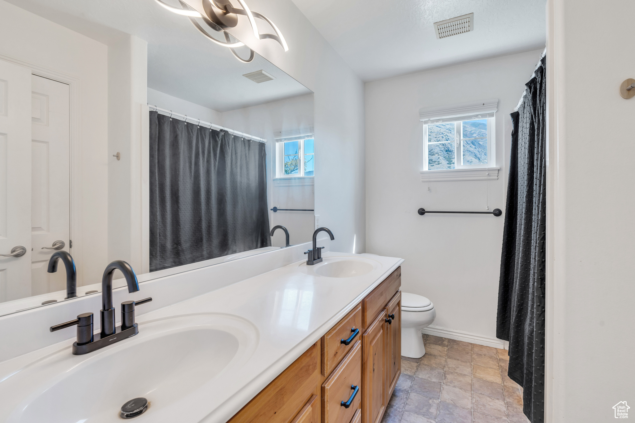 Bathroom with vanity, toilet, and a wealth of natural light