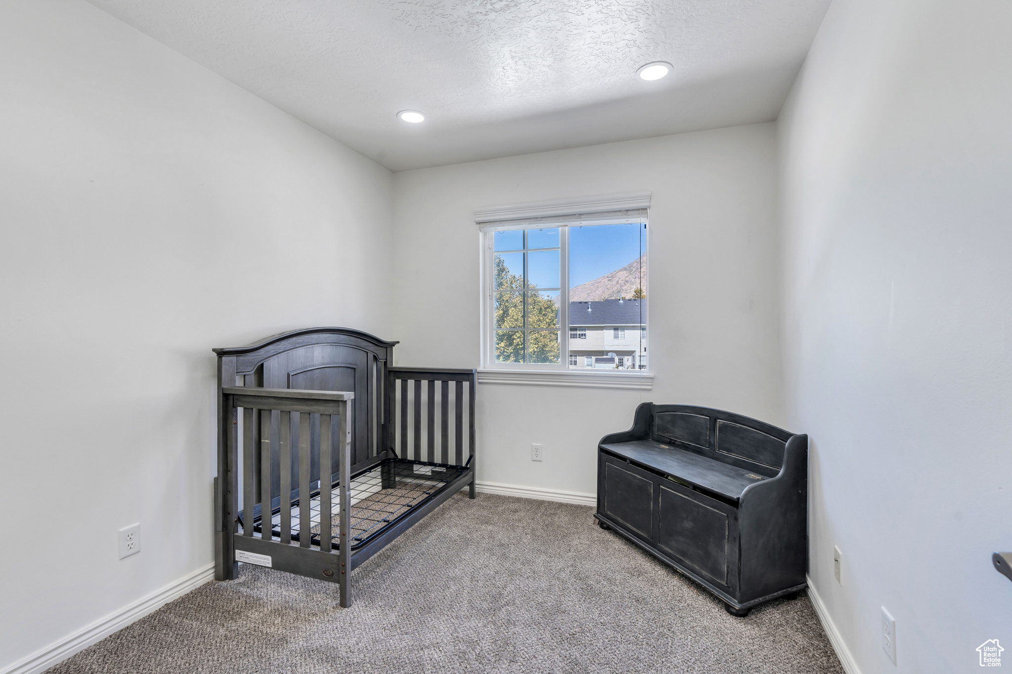 Carpeted bedroom with a crib and a textured ceiling