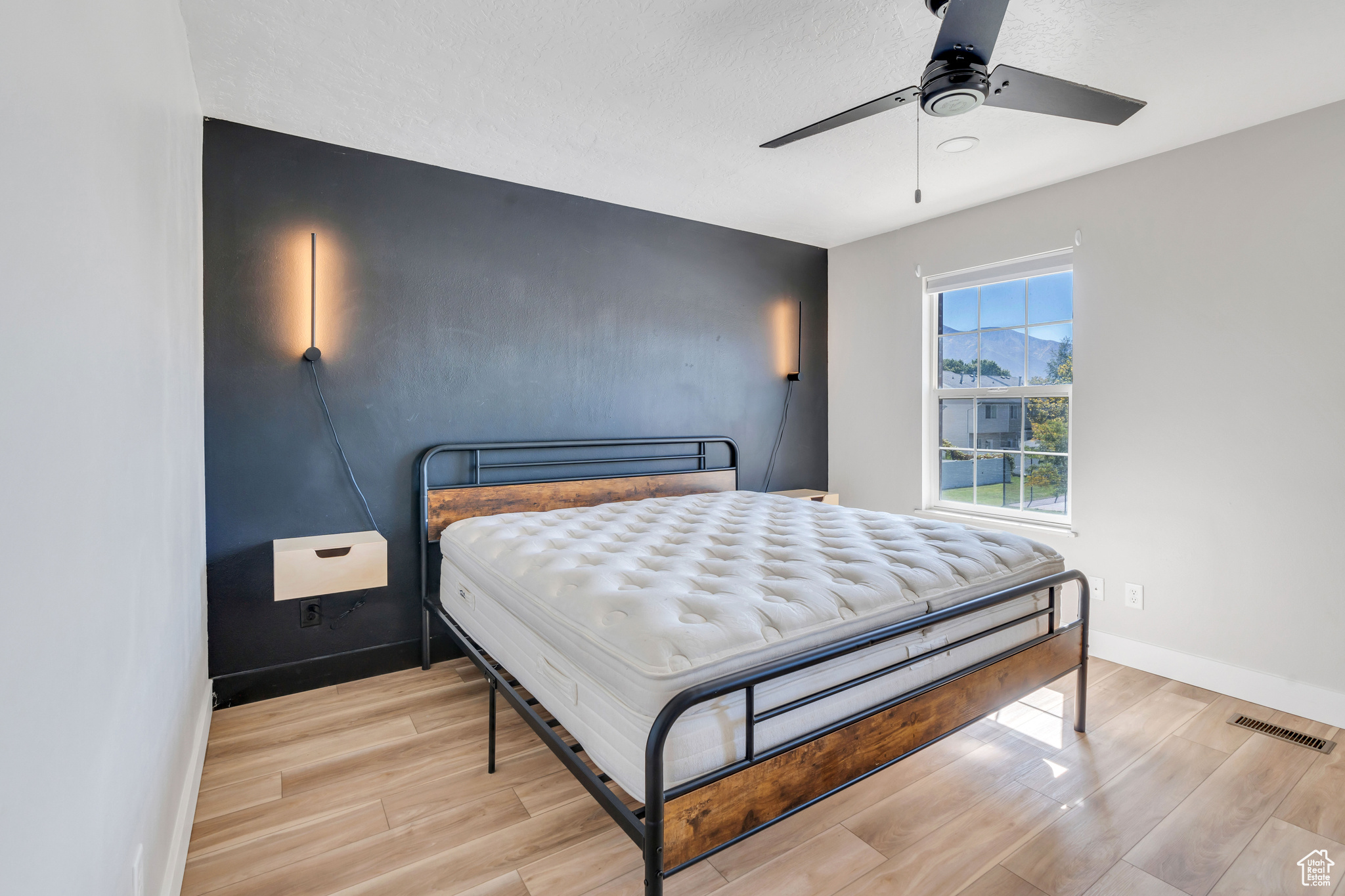 Bedroom featuring light hardwood / wood-style flooring, ceiling fan, and a textured ceiling