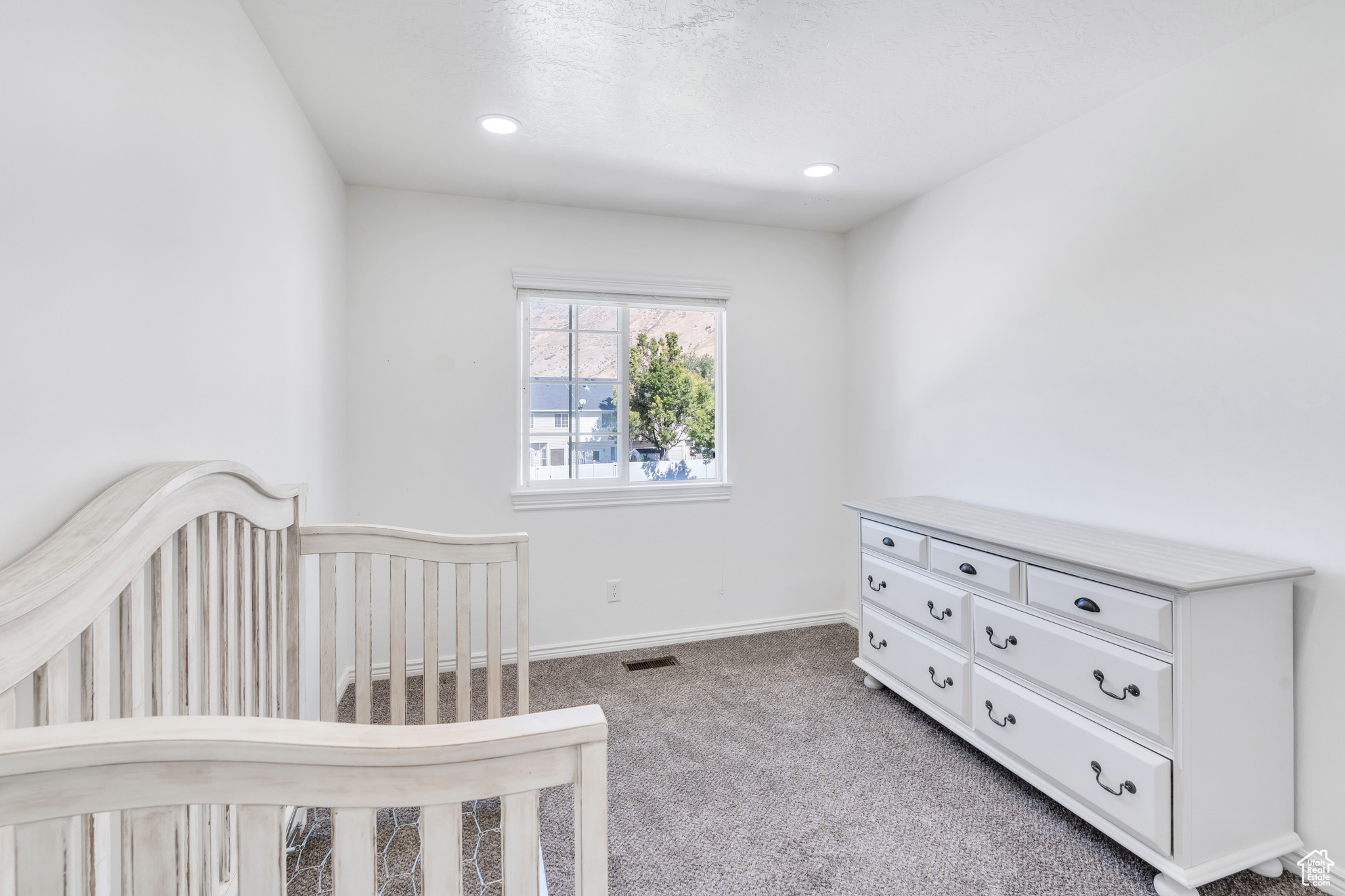 Carpeted bedroom featuring a crib