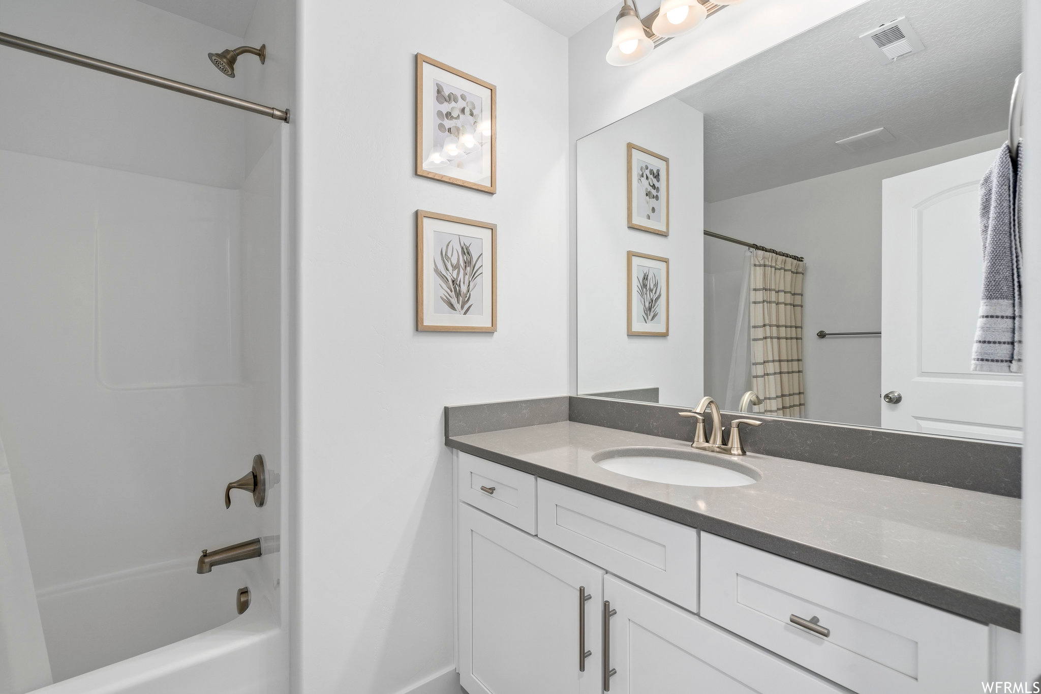 Bathroom featuring large vanity and shower / bath combination with curtain