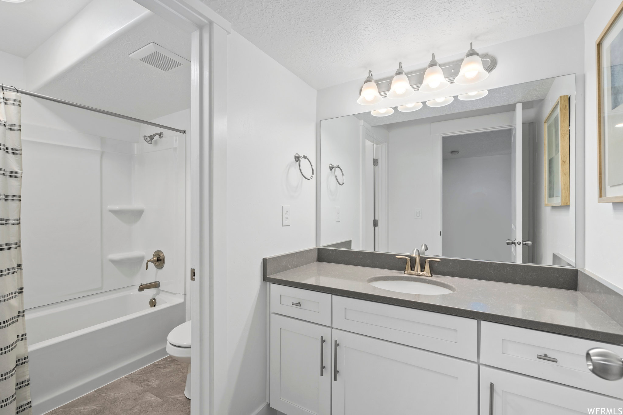 Full bathroom featuring vanity, shower / bath combination with curtain, a textured ceiling, toilet, and tile floors