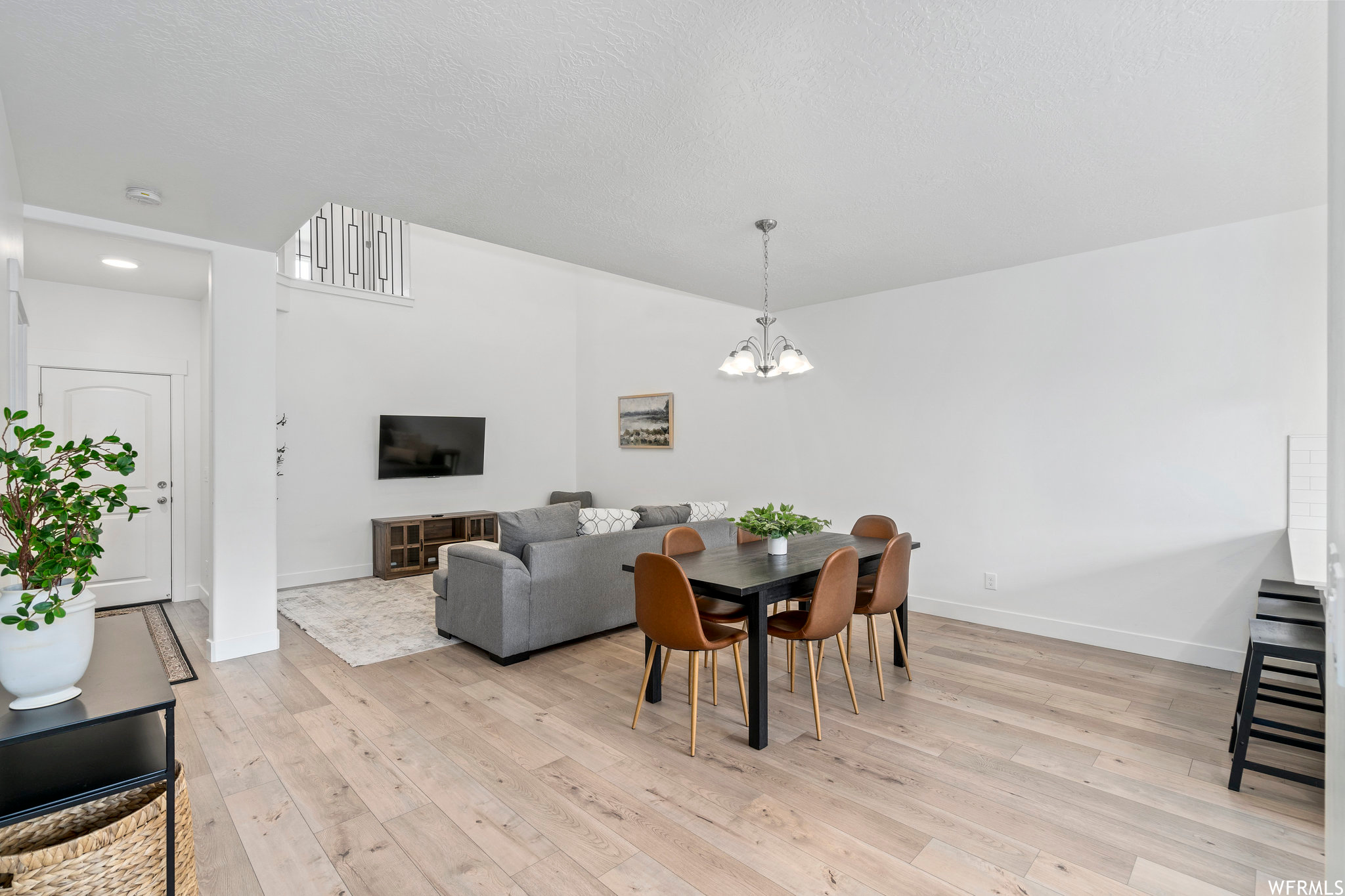 Dining area featuring light wood-type flooring, a textured ceiling, and an inviting chandelier