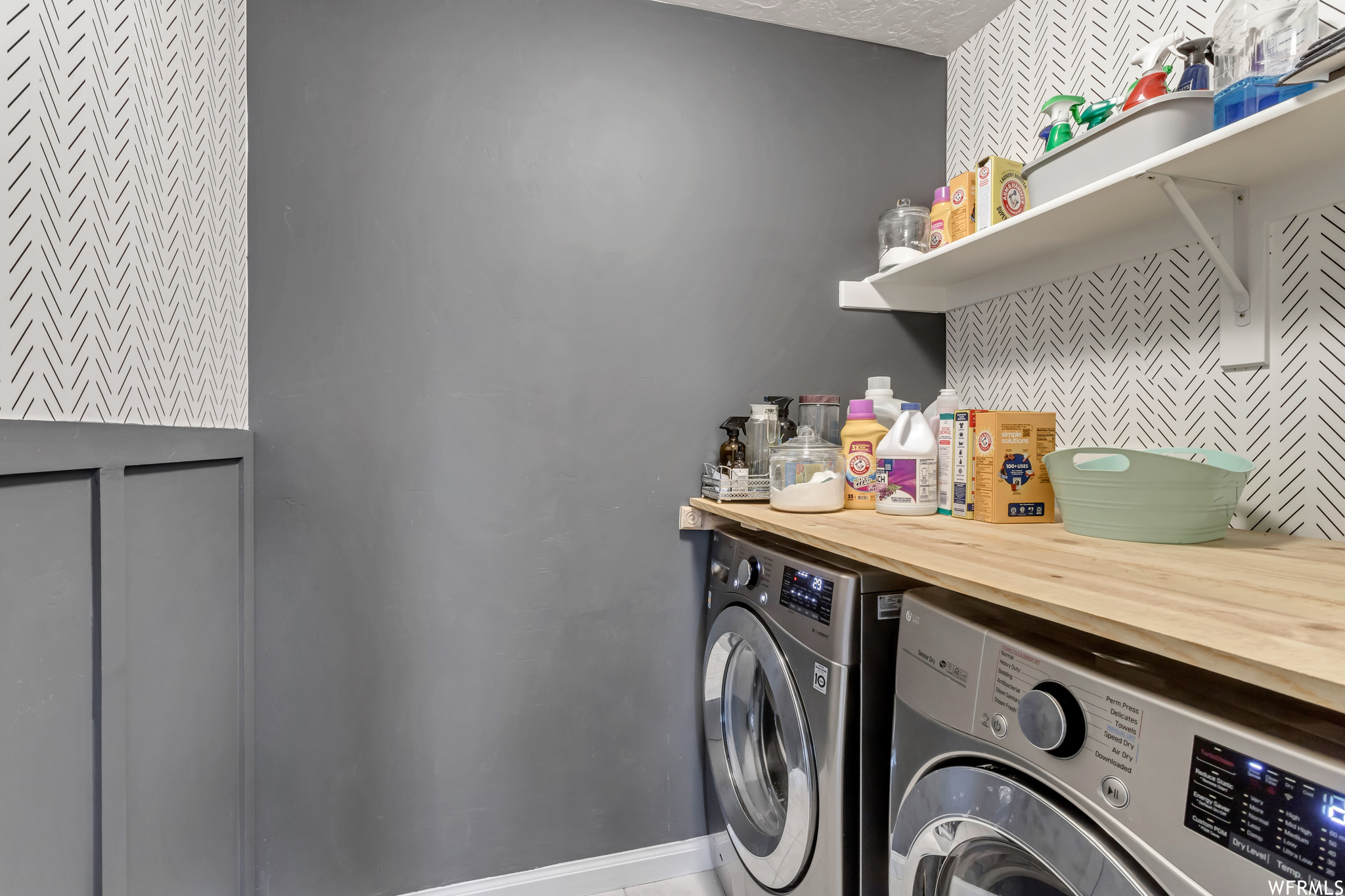 Clothes washing area featuring washing machine and dryer and a textured ceiling