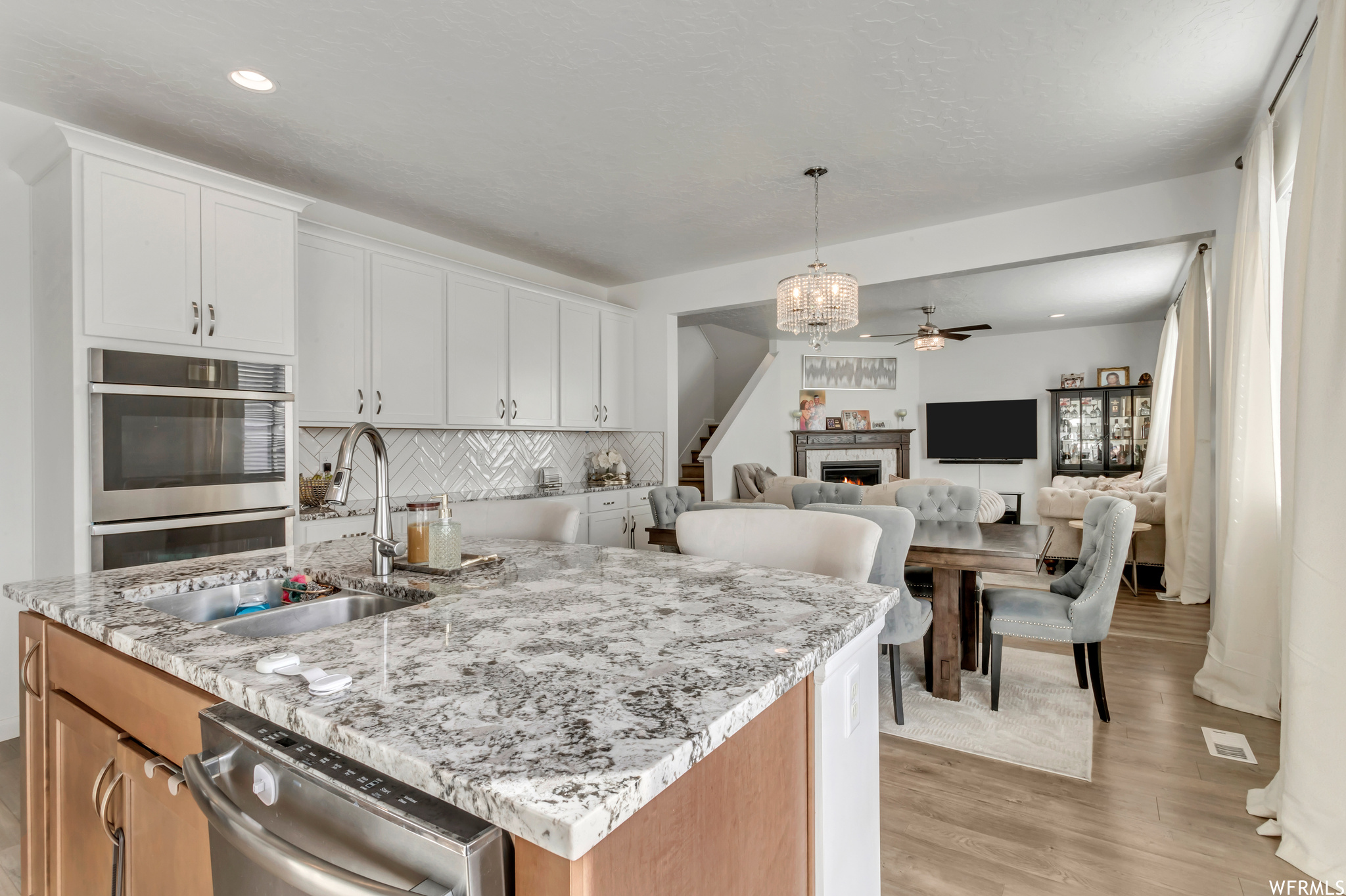 Kitchen with a center island with sink, appliances with stainless steel finishes, tasteful backsplash, light wood-type flooring, and white cabinetry