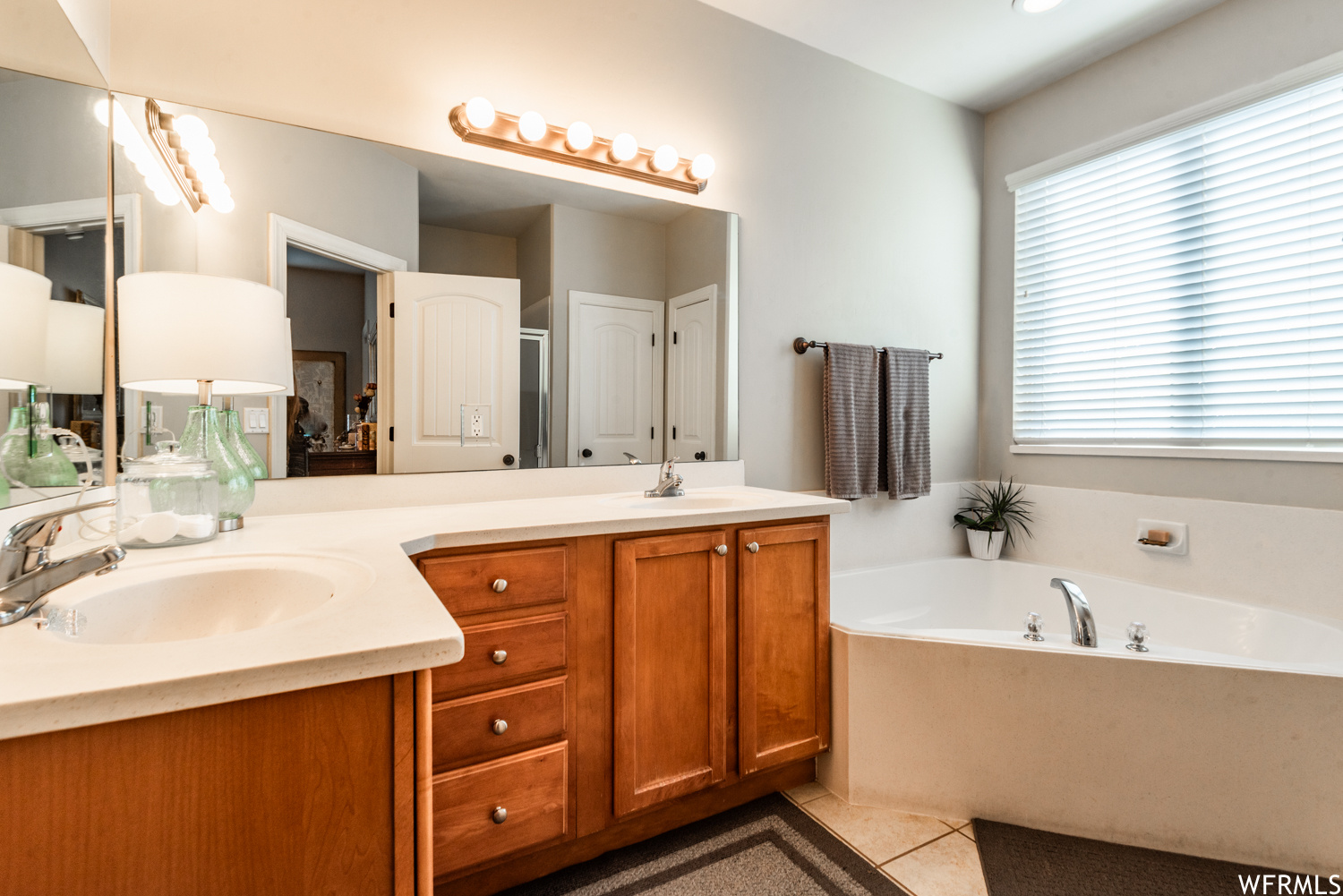 Bathroom featuring tile flooring, a wealth of natural light, a washtub, and double vanity