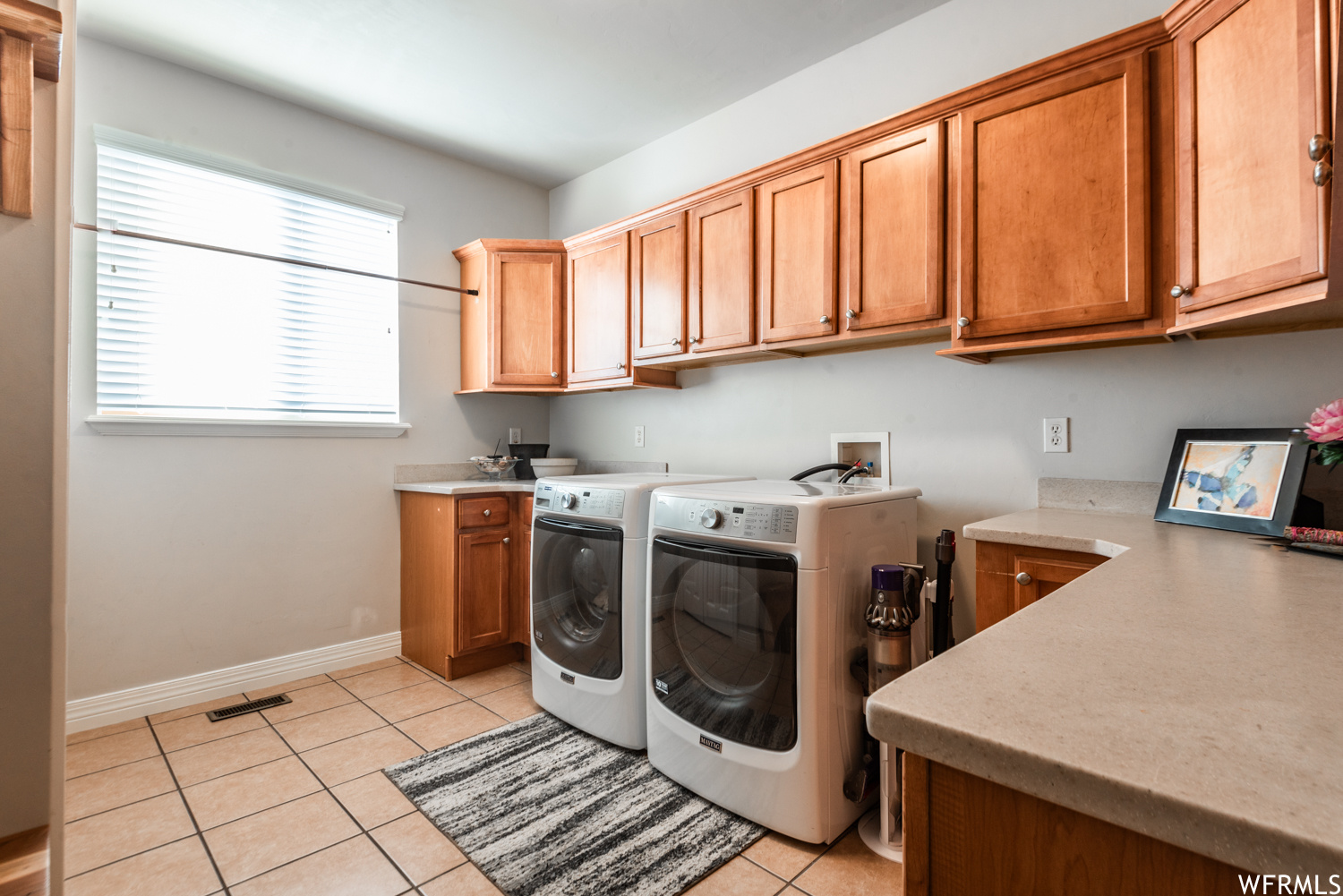 Washroom with light tile floors, cabinets, hookup for a washing machine, and washer and dryer