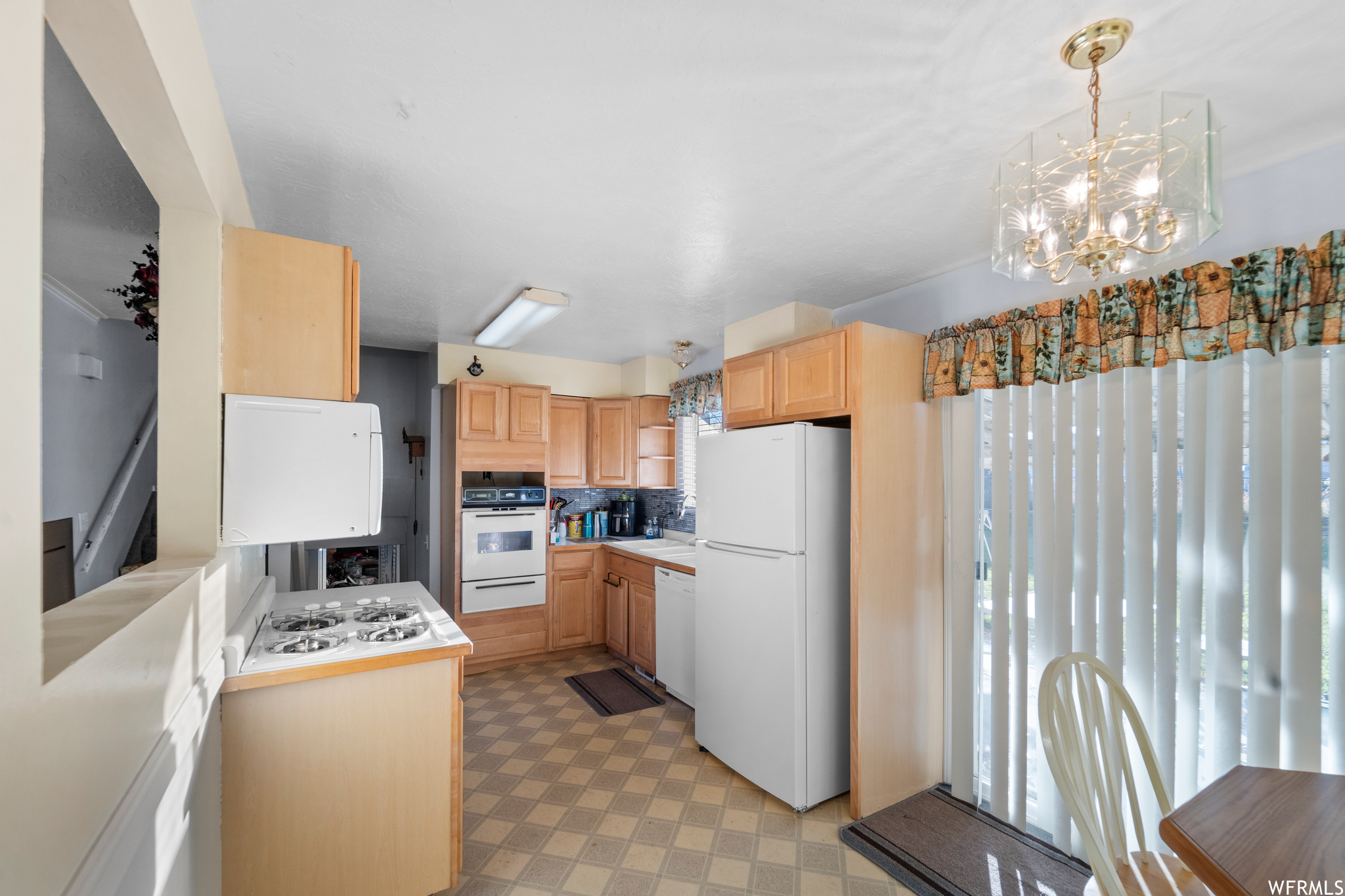 Kitchen featuring white appliances, plenty of natural light, a chandelier, and decorative light fixtures