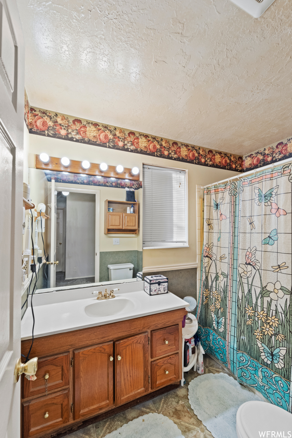 Bathroom with toilet, tile floors, a textured ceiling, and vanity