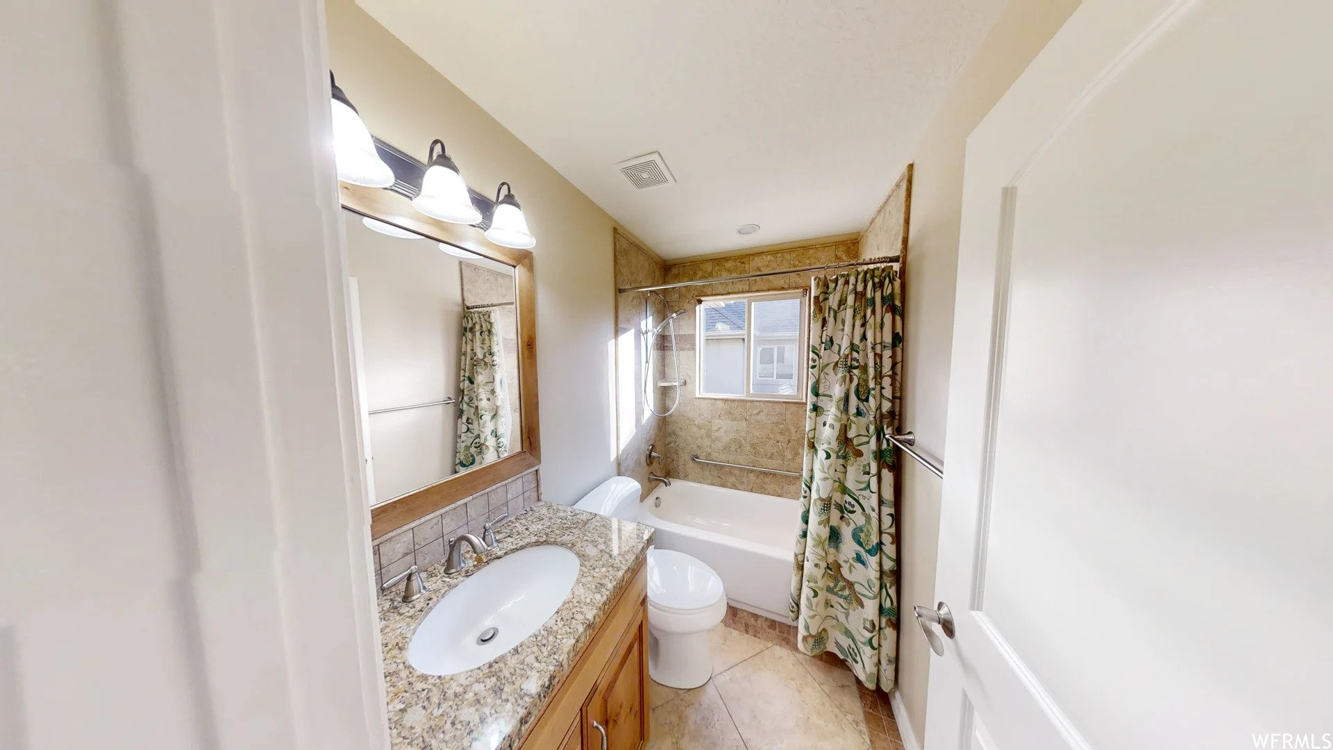Full bathroom featuring toilet, shower / tub combo, large vanity, and tile flooring