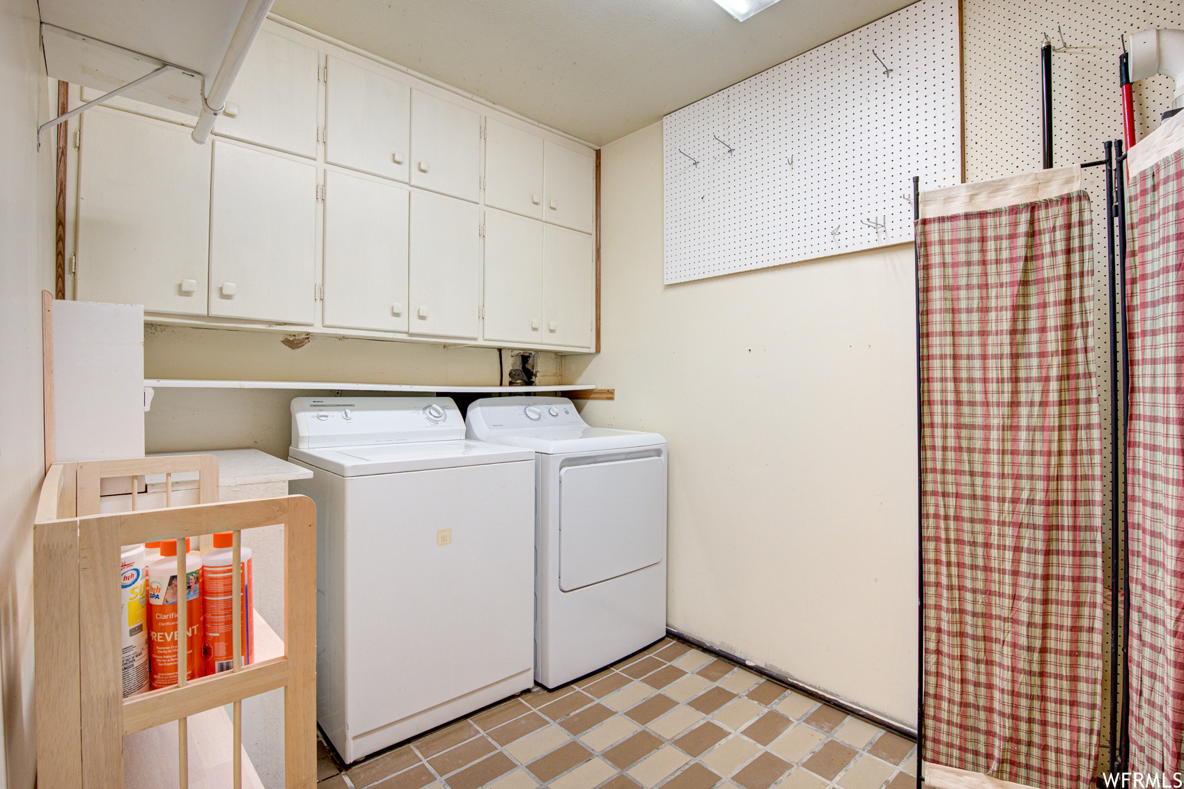 Laundry room featuring cabinets, separate washer and dryer, and light tile floors