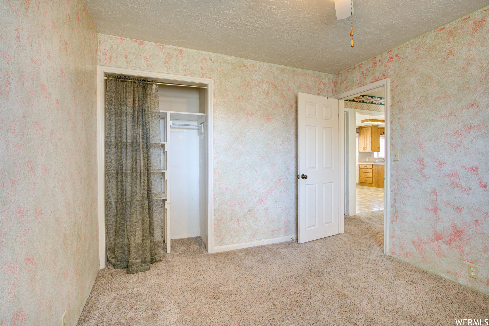 Unfurnished bedroom with ceiling fan, a closet, light colored carpet, and a textured ceiling