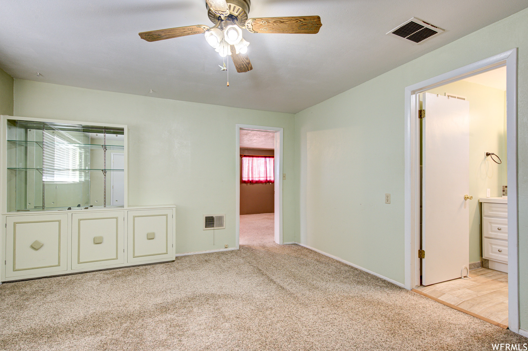 Unfurnished bedroom featuring ensuite bathroom, ceiling fan, and light tile flooring