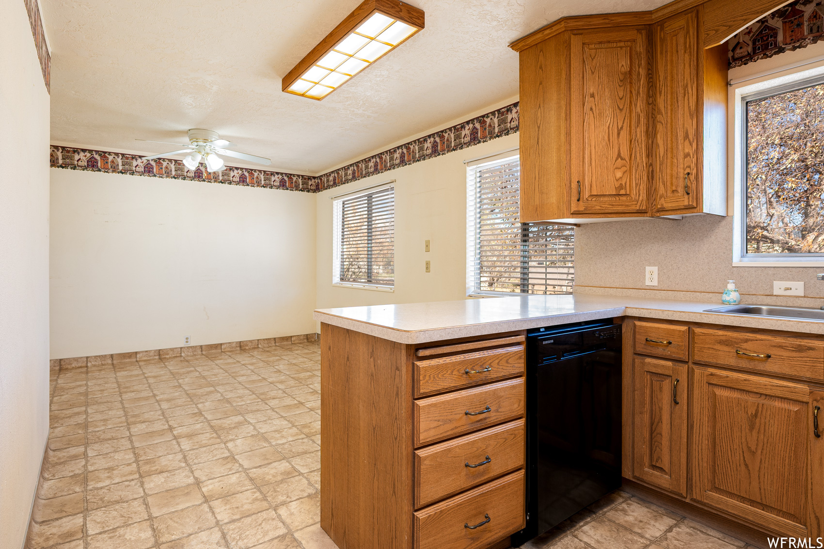 Kitchen with ceiling fan, kitchen peninsula, black dishwasher, and light tile floors