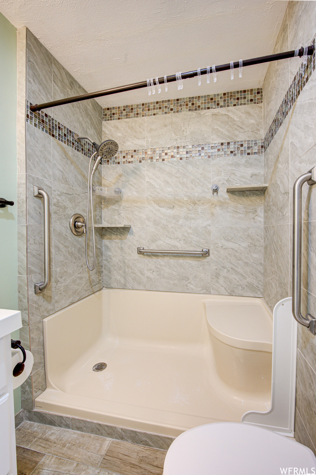 Bathroom with vanity, a textured ceiling, toilet, and a tile shower