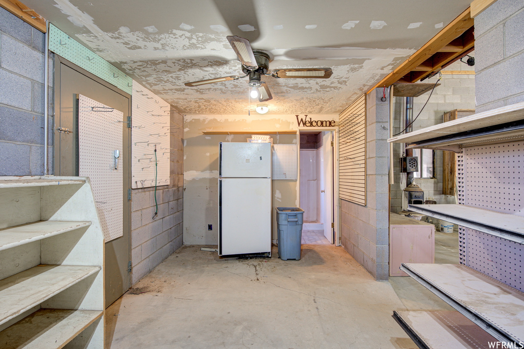 Basement with ceiling fan and white refrigerator