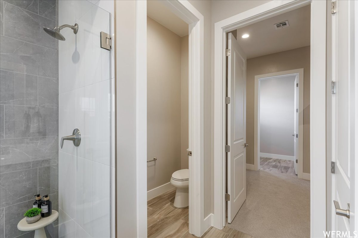 Bathroom featuring toilet, hardwood / wood-style flooring, and a tile shower