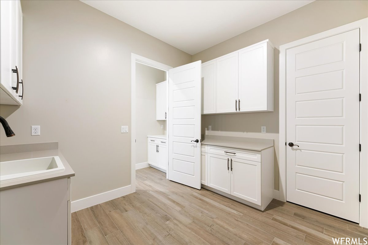 Interior space featuring sink, light hardwood / wood-style flooring, and white cabinetry