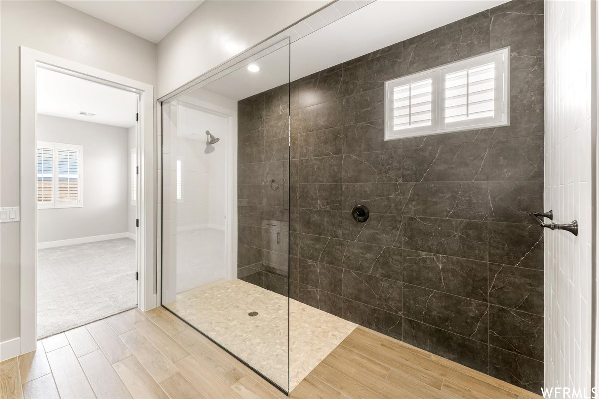 Bathroom featuring tiled shower and hardwood / wood-style floors