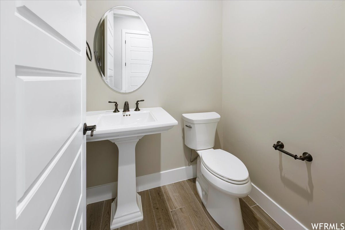 Bathroom featuring toilet, sink, and wood-type flooring
