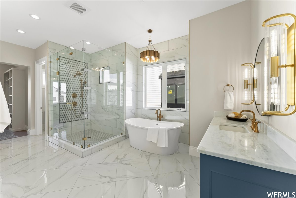 Bathroom with tile walls, an inviting chandelier, plus walk in shower, tile floors, and vanity