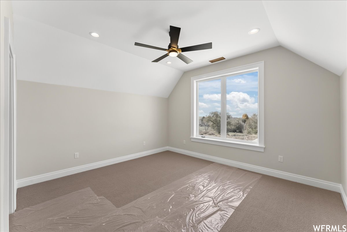 Additional living space with lofted ceiling, ceiling fan, and carpet flooring