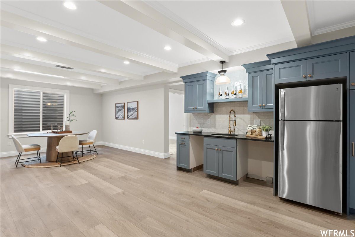 Kitchen with sink, light hardwood / wood-style floors, stainless steel fridge, backsplash, and beam ceiling