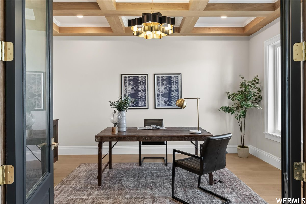 Office space with coffered ceiling, crown molding, light hardwood / wood-style flooring, and a chandelier