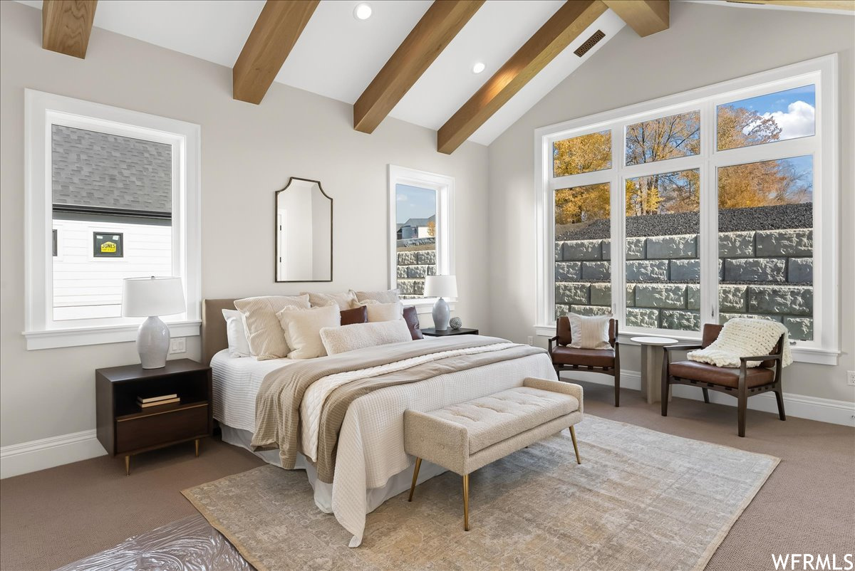 Carpeted bedroom with vaulted ceiling with beams