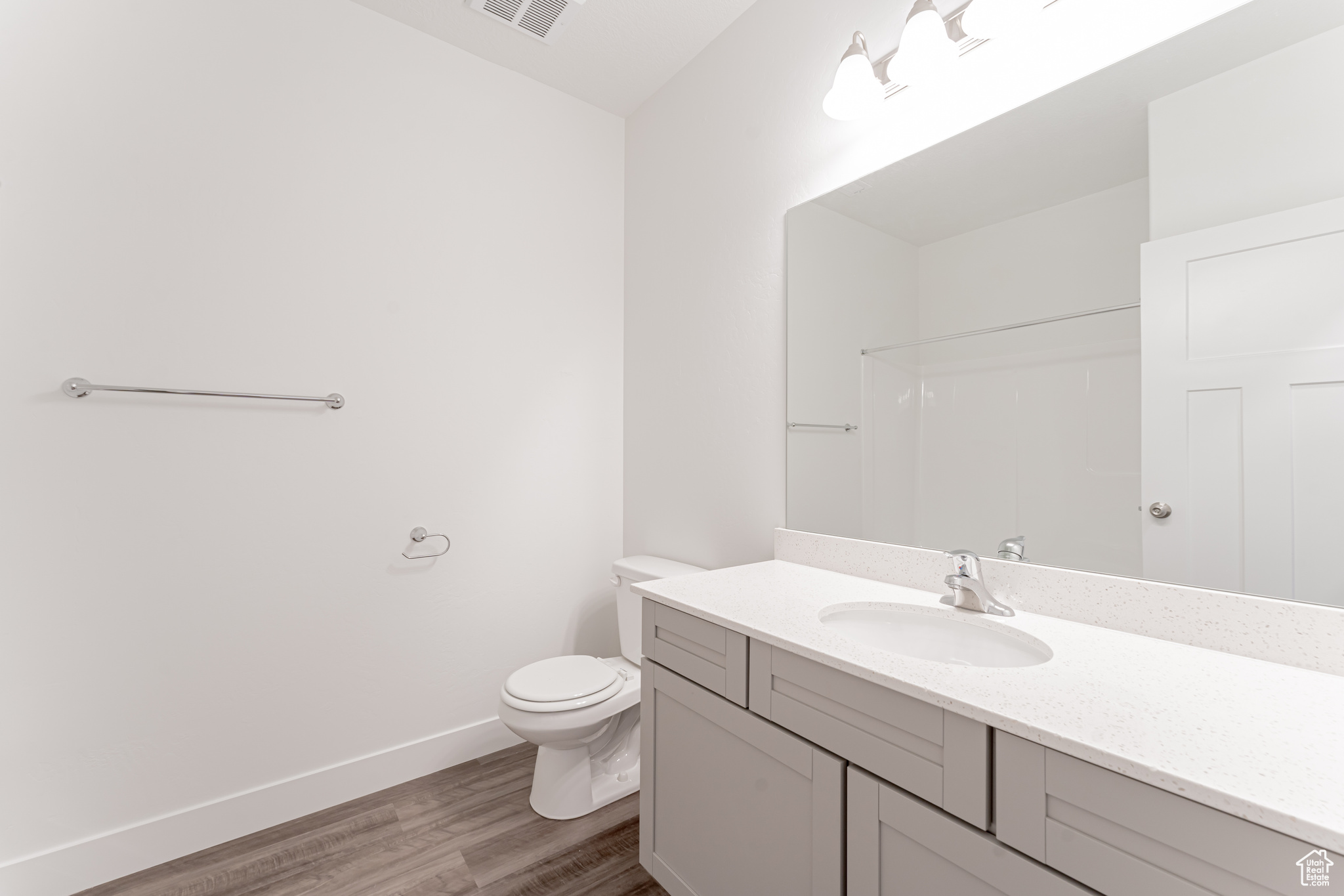 Bathroom featuring toilet, large vanity, and wood-type flooring