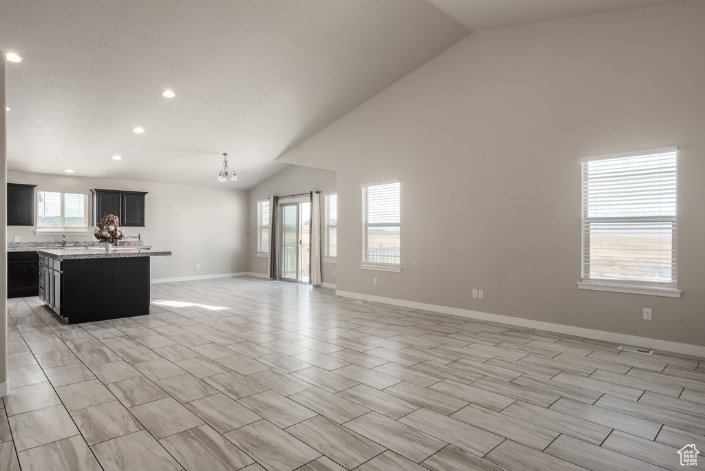Unfurnished living room featuring high vaulted ceiling and light tile floors