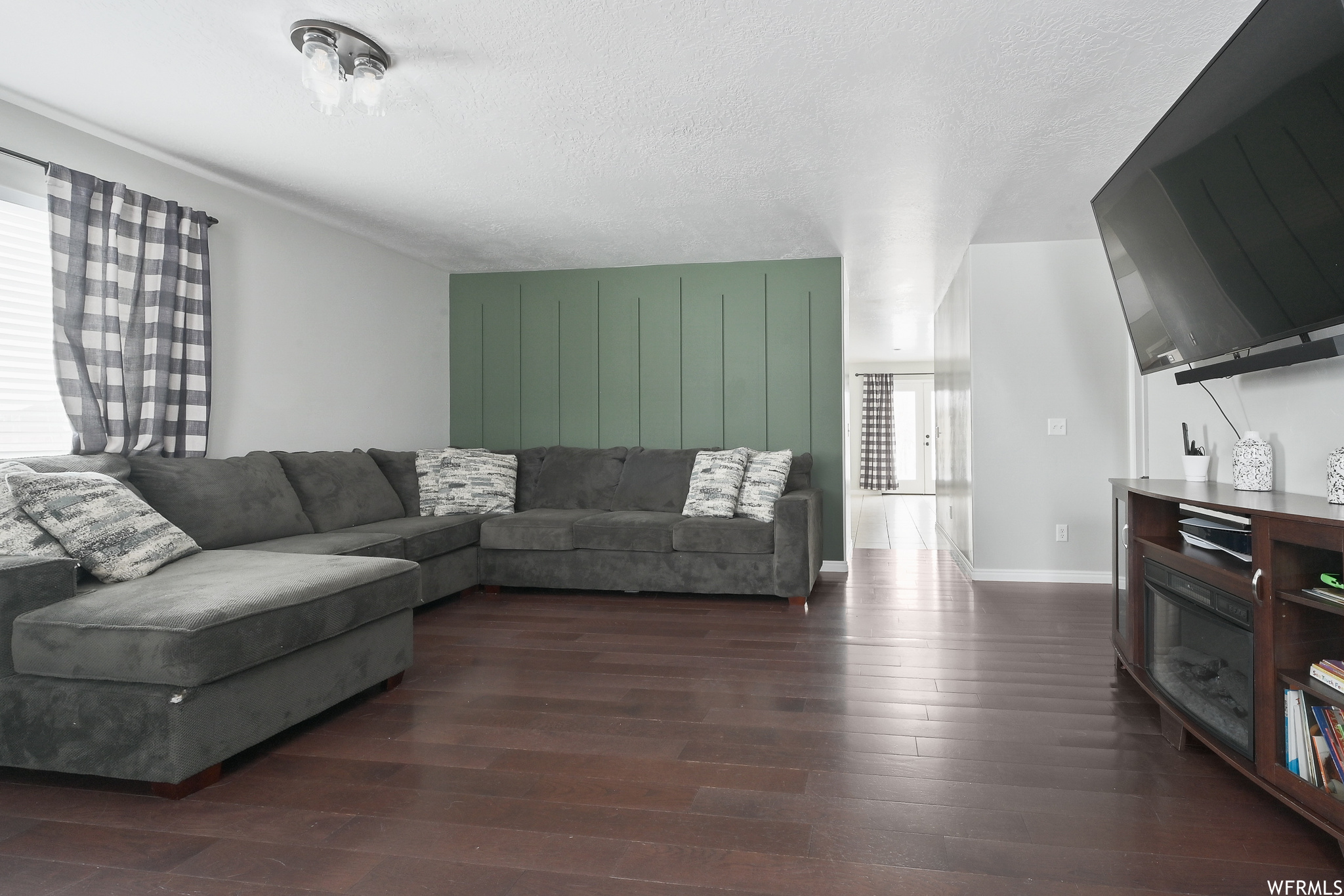 Living room featuring dark wood-type flooring and a textured ceiling