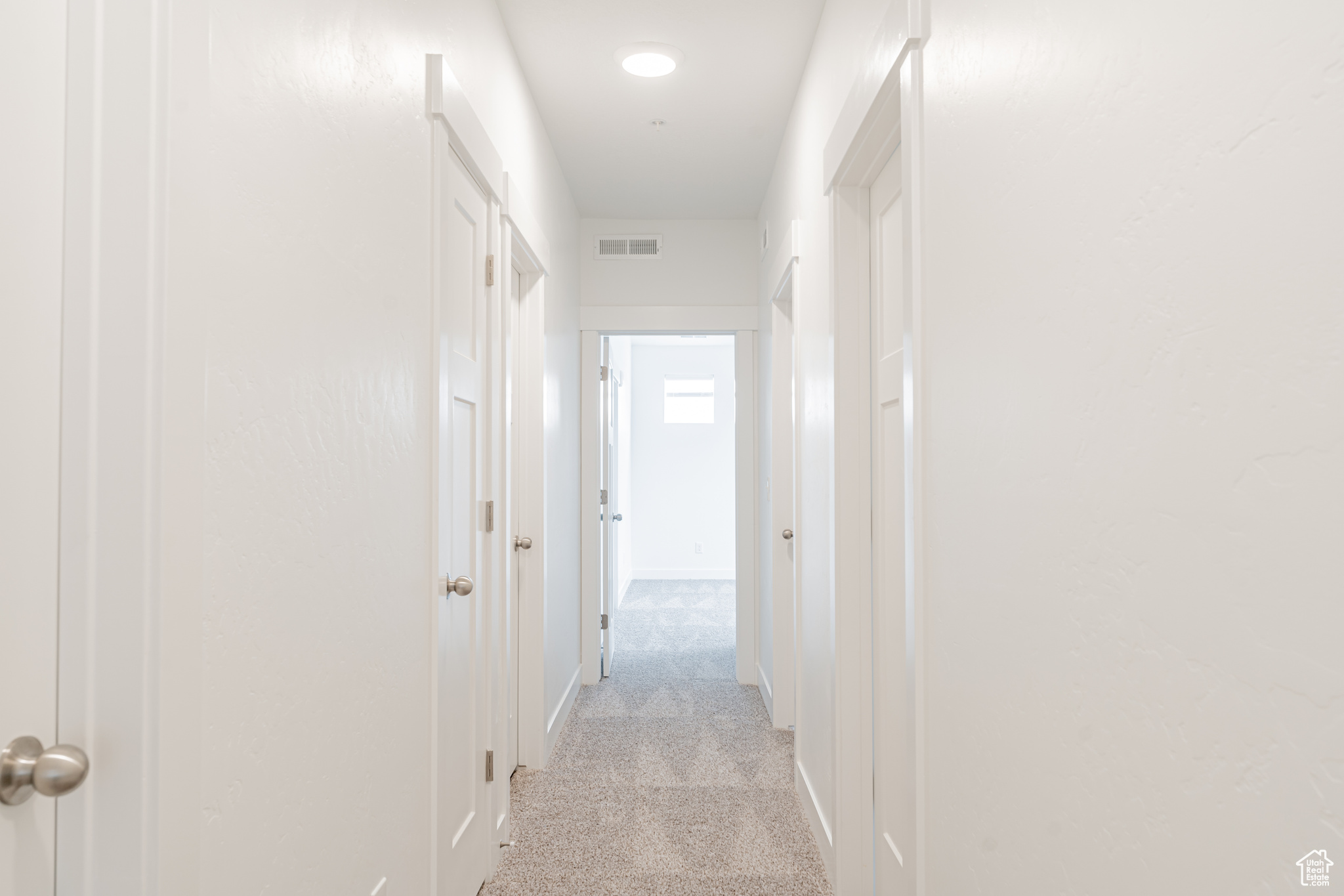 Corridor featuring light colored carpet