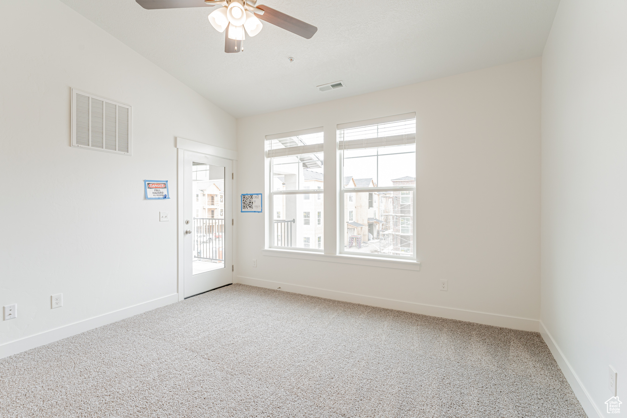 Spare room with ceiling fan, light colored carpet, and vaulted ceiling