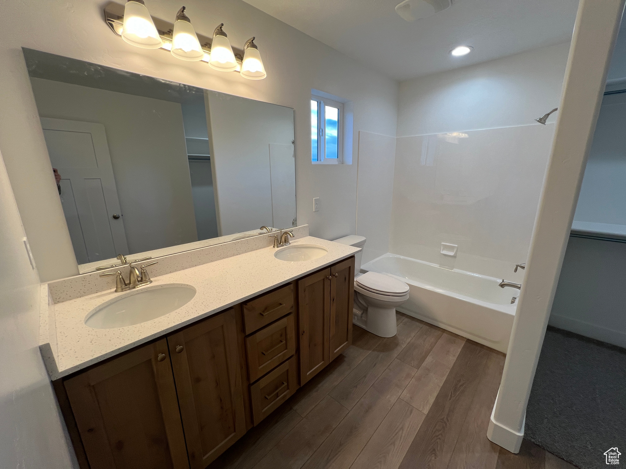 Full master bathroom featuring hardwood / wood-style flooring, shower / washtub combination, large vanity, toilet, and double sink
