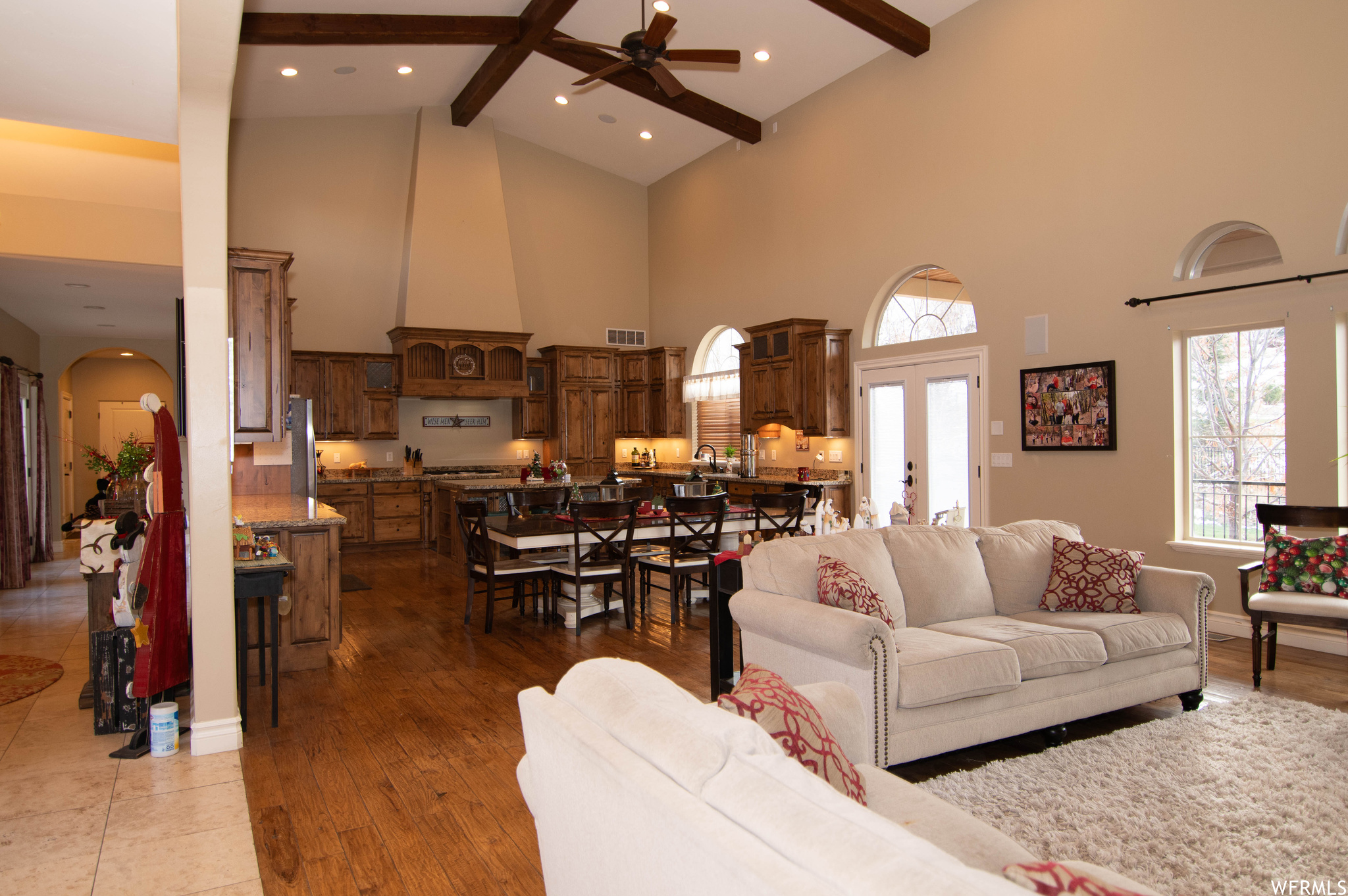 Living room with ceiling fan, beam ceiling, hardwood / wood-style floors, and high vaulted ceiling