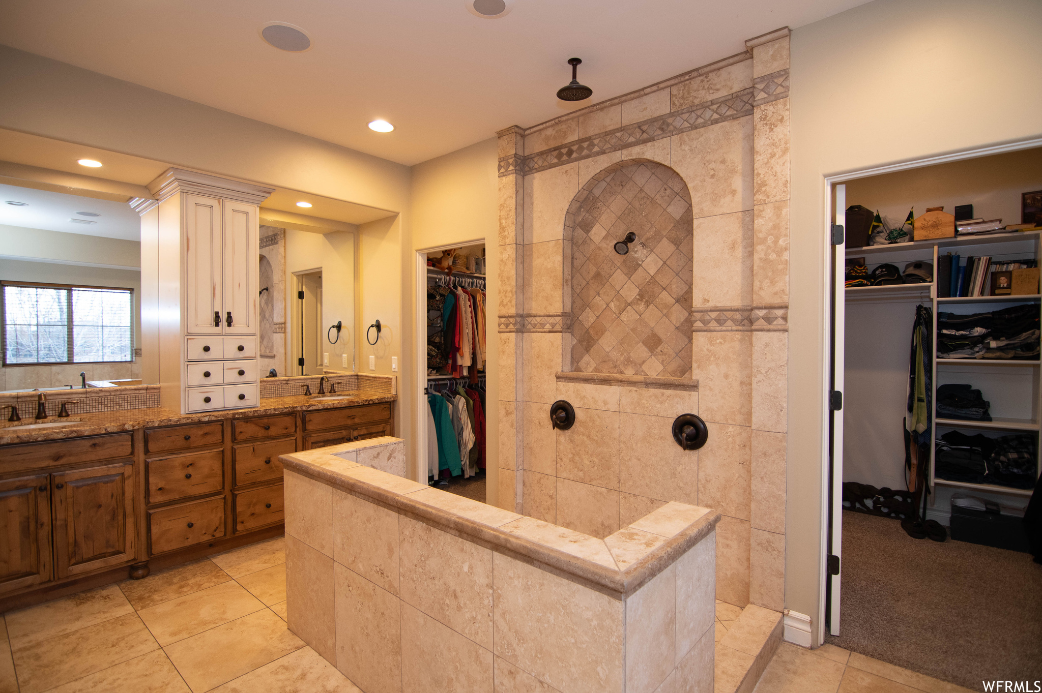 Bathroom featuring ornate columns, tile flooring, double sink vanity, and a tile shower