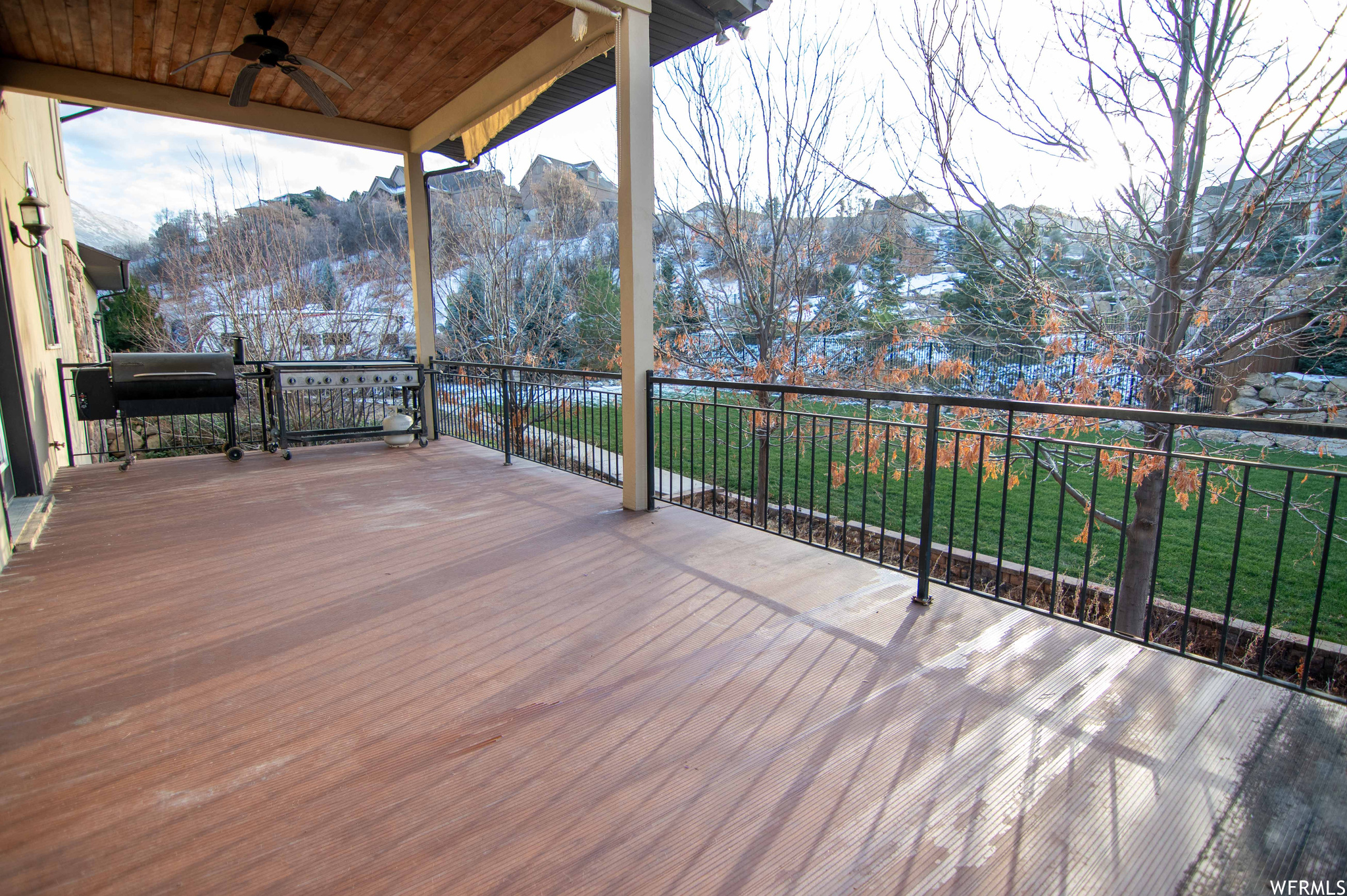 Wooden deck with ceiling fan, a yard, and a mountain view