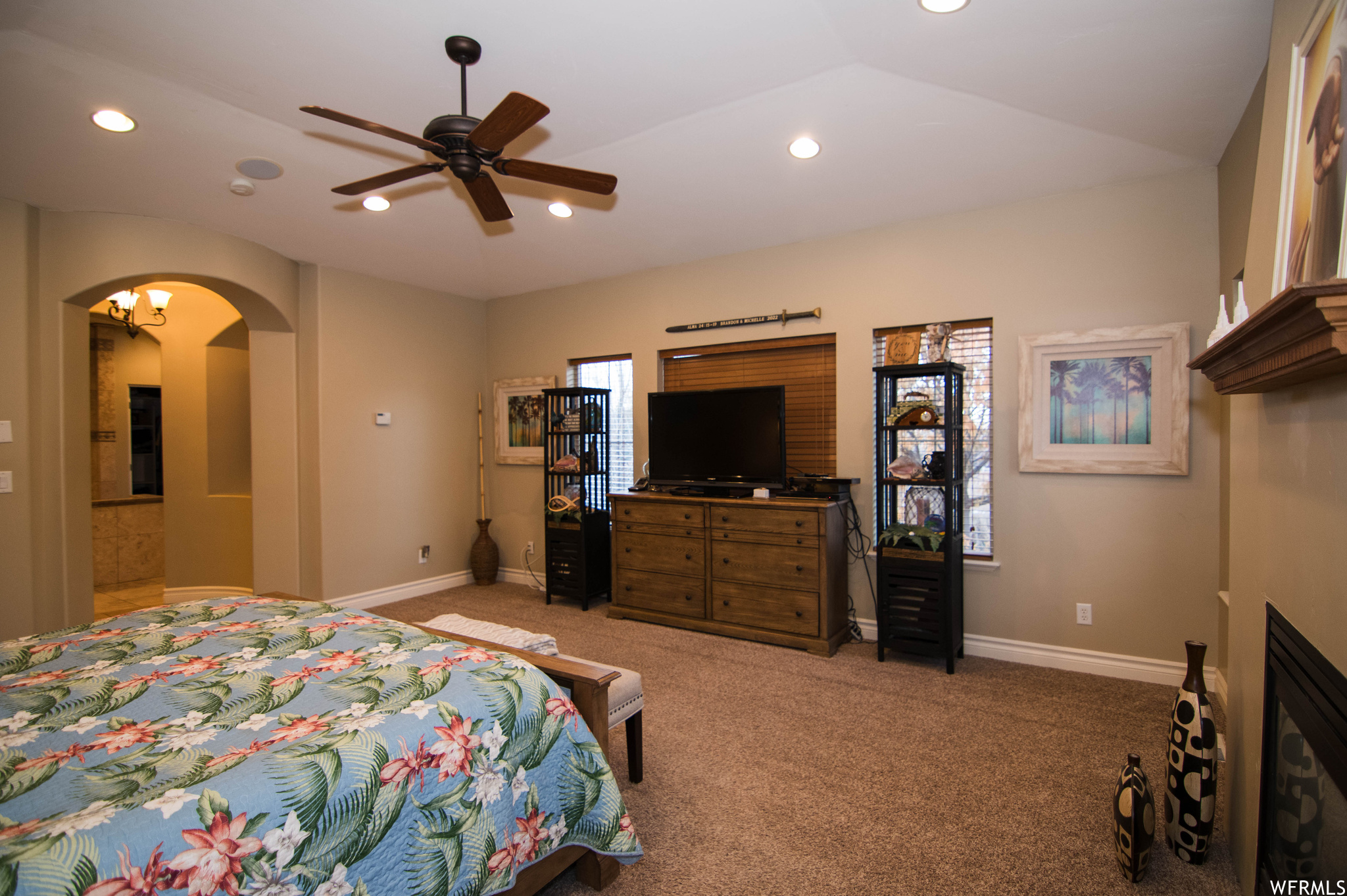 Bedroom with lofted ceiling, ceiling fan, connected bathroom, and light carpet