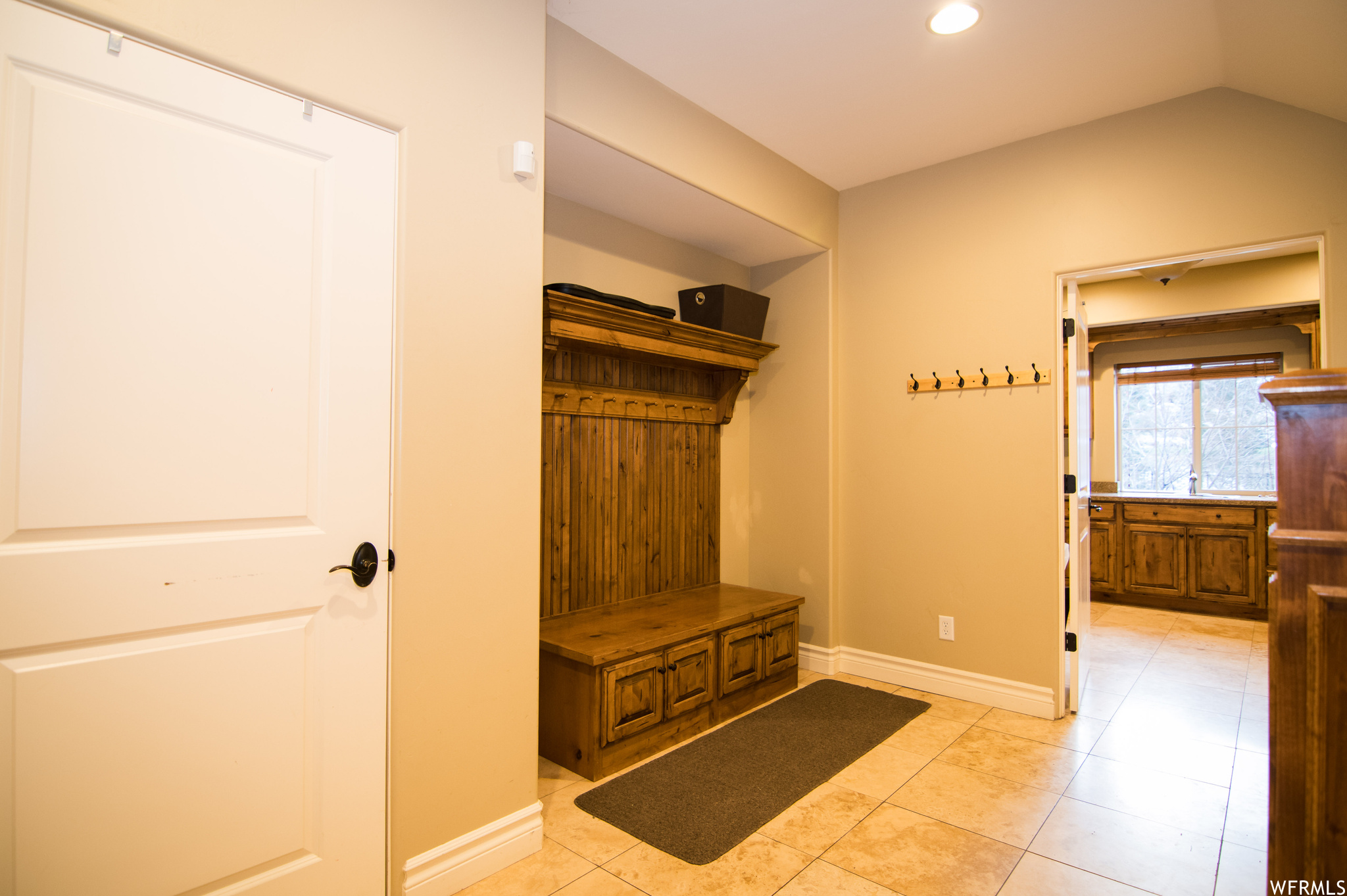Mudroom featuring vaulted ceiling, sink, and light tile floors
