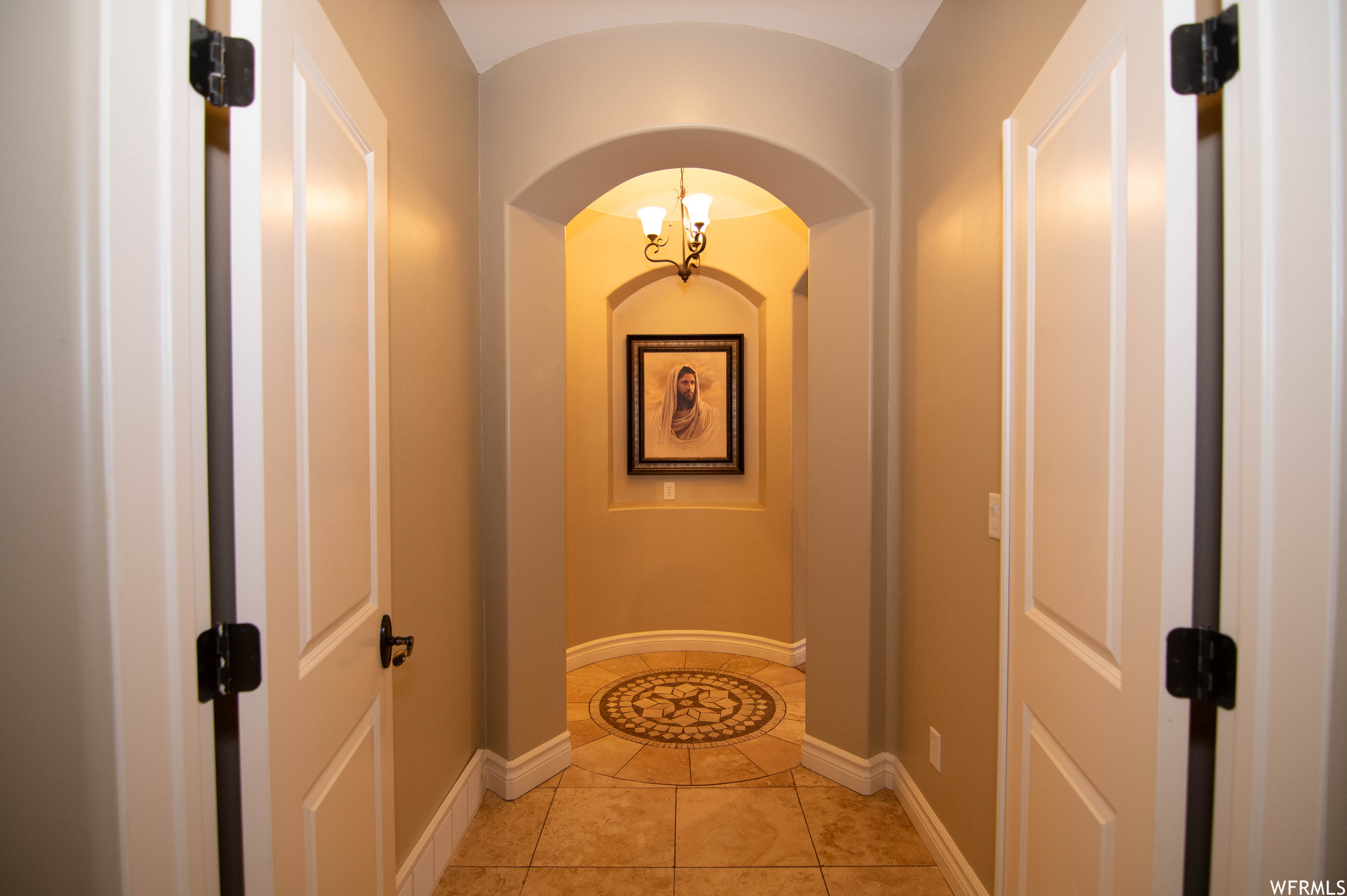 Hallway with an inviting chandelier and light tile floors