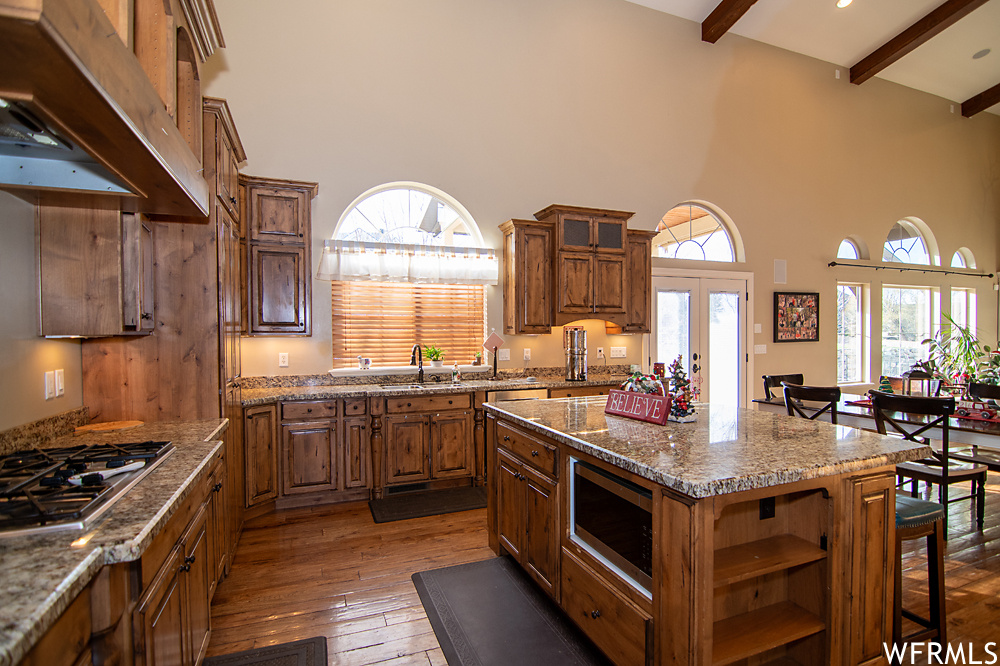 Kitchen with a center island, light stone counters, dark hardwood / wood-style flooring, and stainless steel appliances