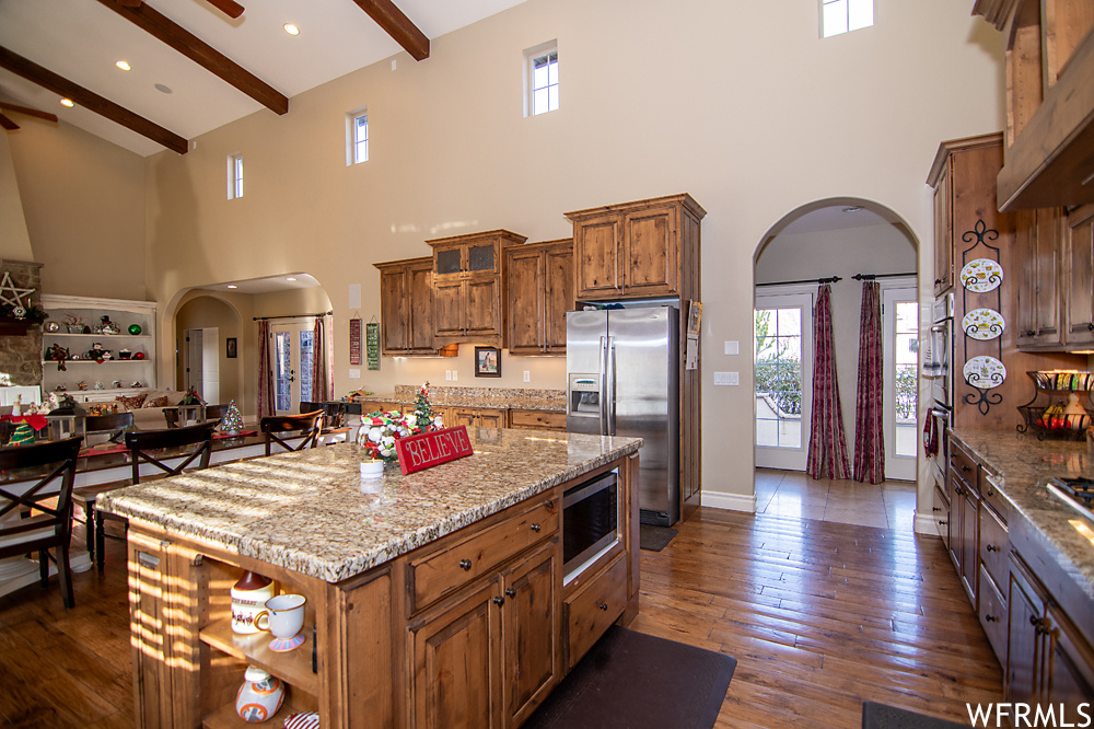 Kitchen with a center island, beam ceiling, high vaulted ceiling, and stainless steel appliances