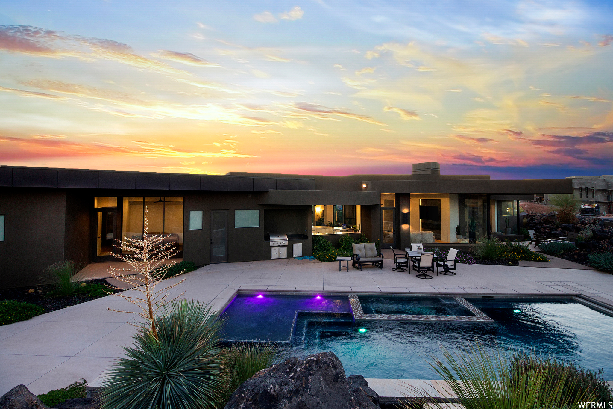 Pool at dusk featuring an outdoor kitchen, a patio area, and area for grilling